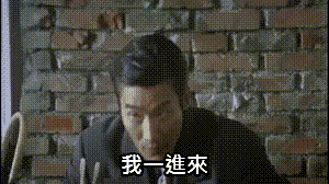 a man in a suit is sitting in front of a brick wall .