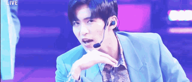 a man wearing a blue suit and a microphone with the word live in the corner