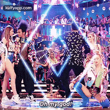 a group of people are dancing on a stage in front of a crowd and one of them is kneeling down .