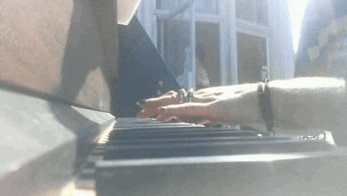 a close up of a person playing a piano with a bracelet on their wrist