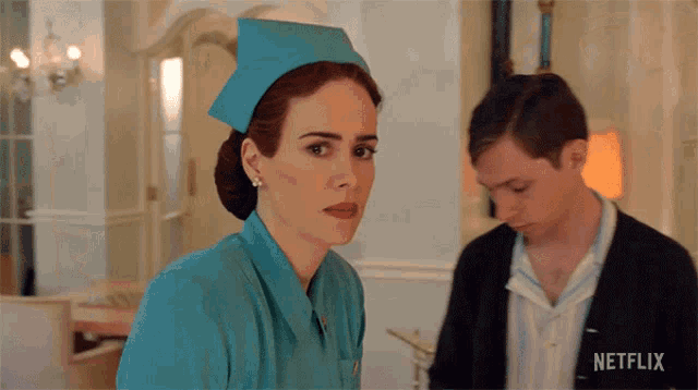 a woman in a nurse 's uniform is standing next to a man with a netflix logo on his shirt