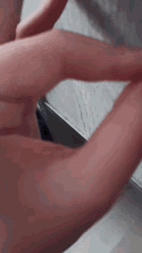 a close up of a person 's hand making a heart with their fingers .