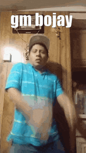 a man in a blue shirt and hat is dancing in front of a wooden wall with the words gm bojay on it