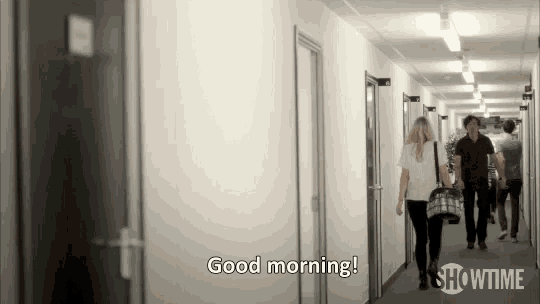 a man and a woman are walking down a hallway and the man says " good morning "
