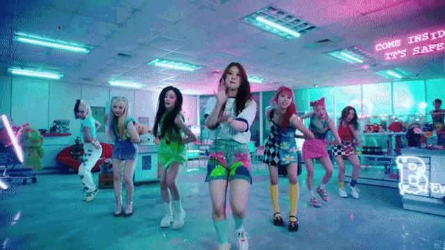 a group of girls are dancing in a room with a sign that says come in it 's safe