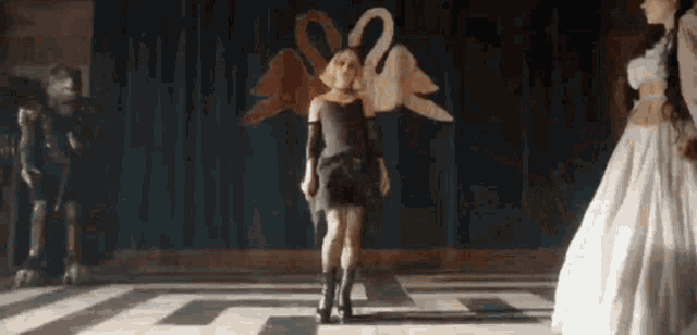 a woman in a black dress is standing in front of a statue of a swan .