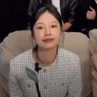 a woman is sitting on a couch with a microphone in her hand and making a funny face .