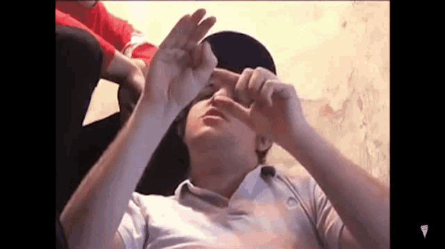 a man is laying on the floor with his hands on his face and making a heart shape with his hands .