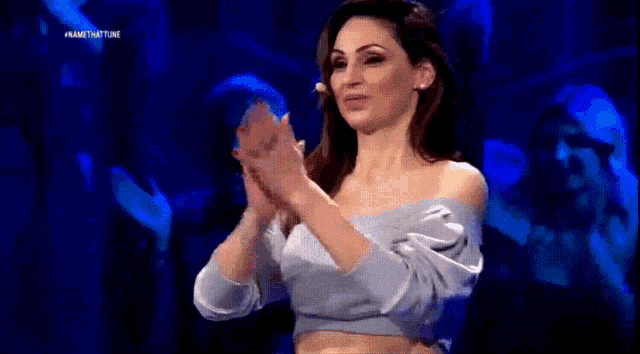 a woman in a blue off the shoulder top is raising her fist in the air ..