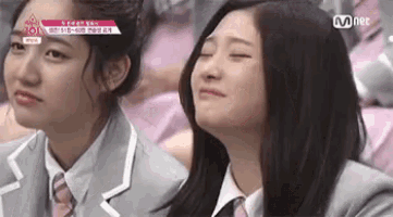 two girls are sitting next to each other and one of them is crying while the other is smiling