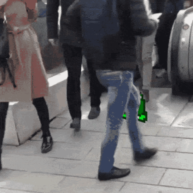 a group of people walking down a sidewalk with a green item in the background