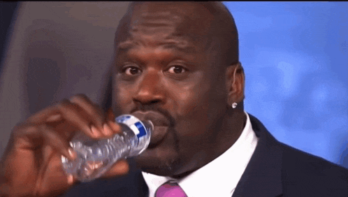 a man in a suit and tie drinks water from a bottle