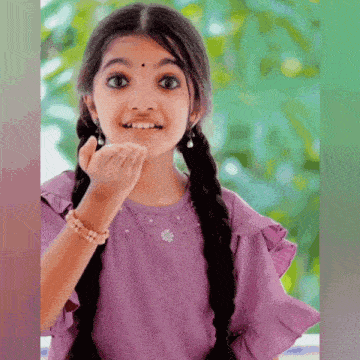 a little girl in a purple dress is blowing a kiss at the camera