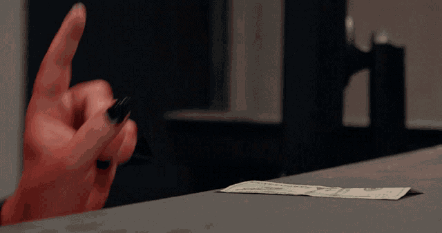 a woman 's hand is pointing at a 20 dollar bill on a counter