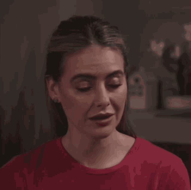 a woman wearing a red shirt is smiling and looking at the camera