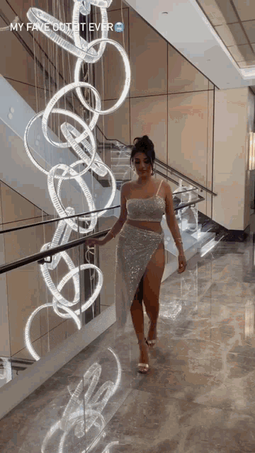 a woman in a silver dress is walking down a staircase