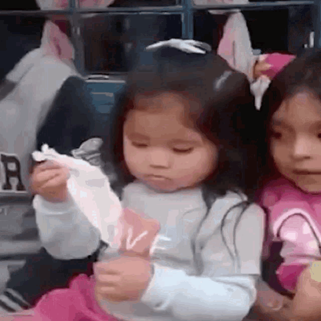 two little girls are sitting next to each other and one is holding a piece of paper that says love on it .