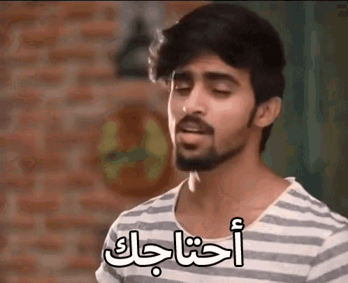 a man with a beard wearing a striped shirt has arabic writing on his shirt