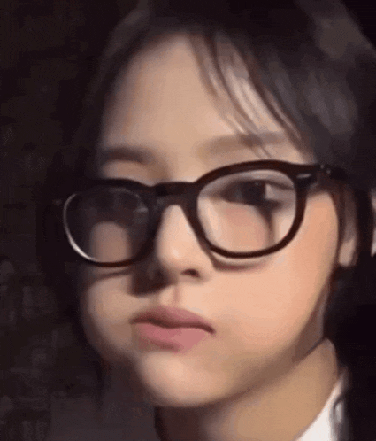 a close up of a girl wearing glasses making a face .