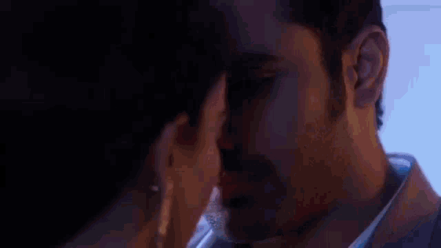 a man and a woman are looking into each other 's eyes and kissing .