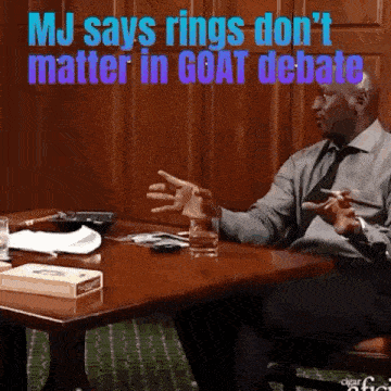 a man sitting at a table with the words mj says rings do n't matter in goat debate below him