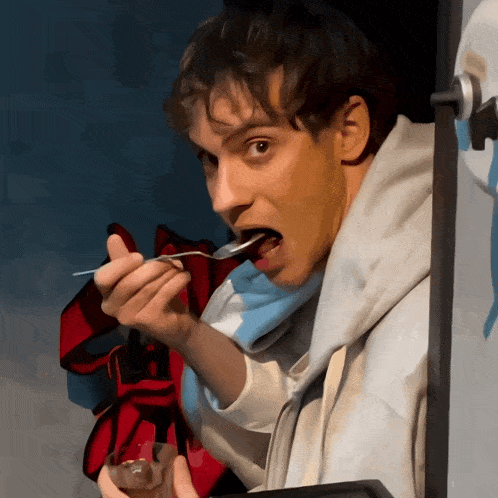 a man is holding a spoon in his mouth and eating something