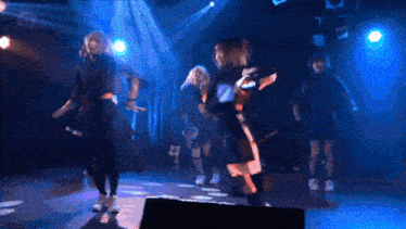 a group of girls are dancing on a stage and one of them is wearing a black shirt with the number 2 on it