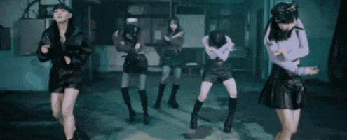a group of young women are dancing together in a dark room