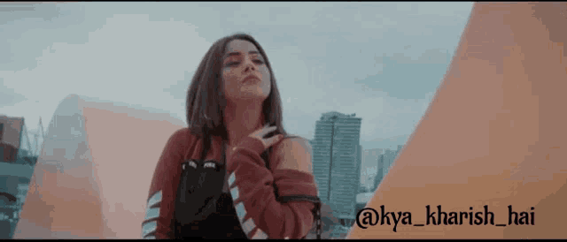 a woman is standing in front of a city skyline with the words @kya_kharish_hai on the bottom
