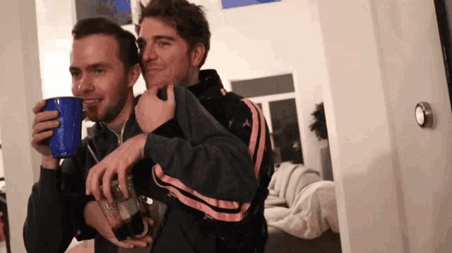 two men are standing next to each other and one is holding a blue cup that says pepsi on it