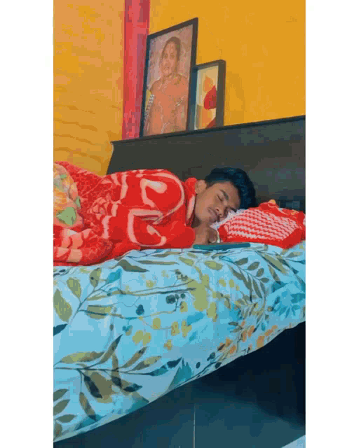 a young man is sleeping on a bed with a picture of a woman on the headboard