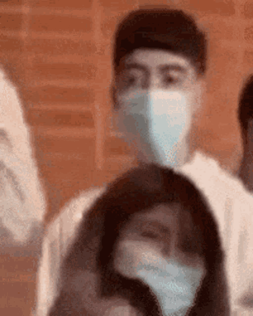 a man wearing a mask is standing in a crowd of people .