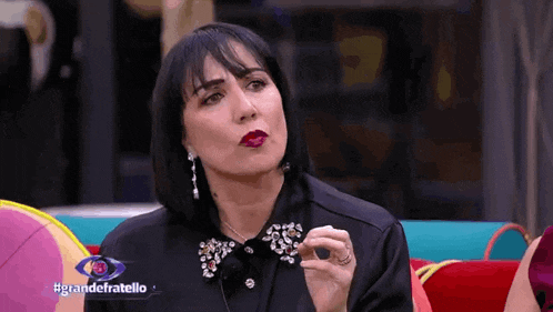 a woman sitting on a couch with the words grandefratello on the bottom right