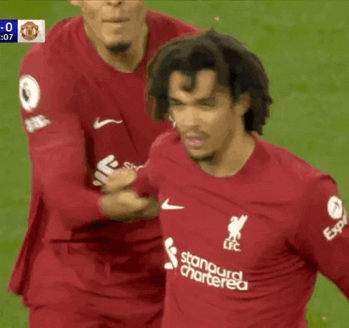 a soccer player wearing a red shirt that says standard chartered