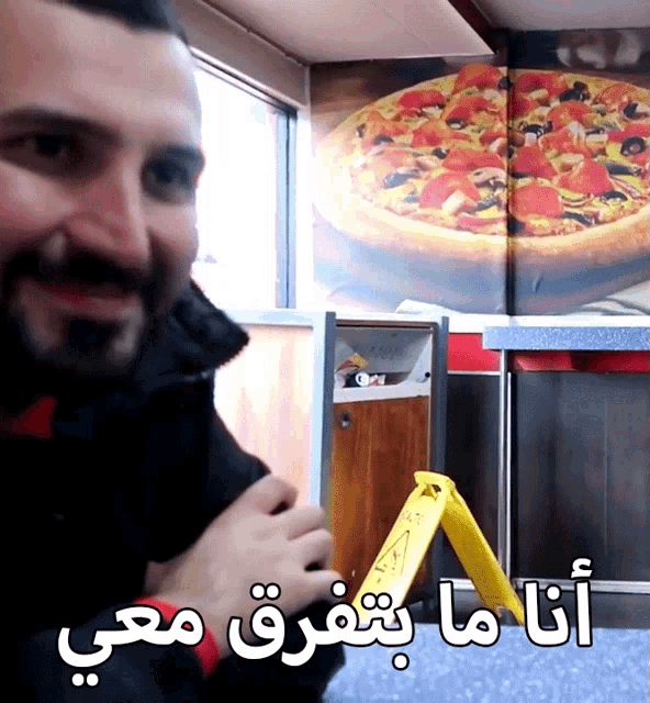 a man in front of a picture of a pizza and a sign that says " i 'm sorry "