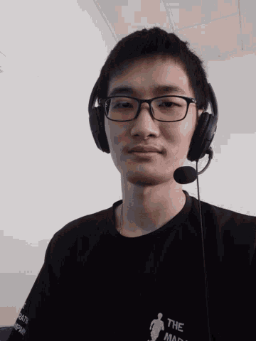 a man wearing glasses and headphones has a shirt that says " the man " on it