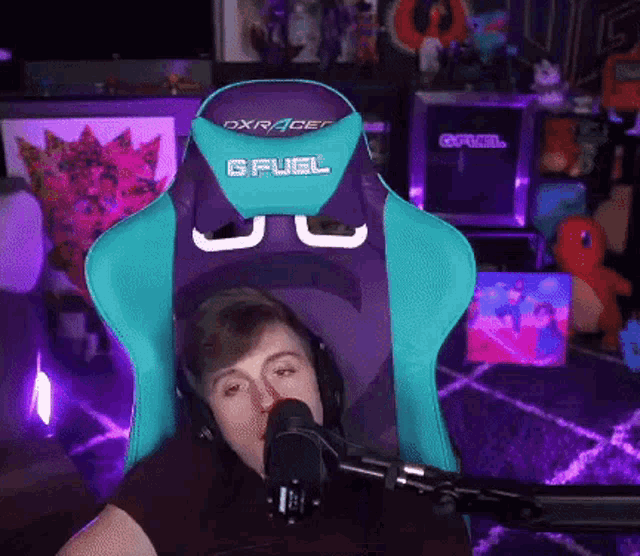 a man wearing headphones is sitting in a blue and purple gfuel chair