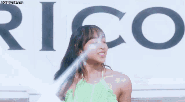 a woman in a green top is dancing in front of a sign that says eric