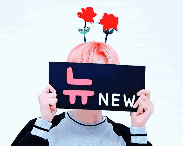 a person holding up a sign that says new