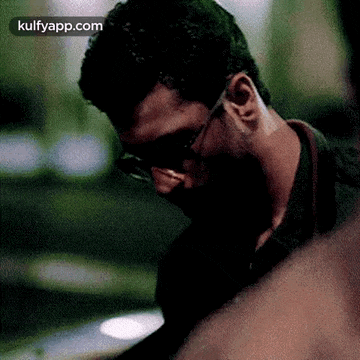 a close up of a man wearing sunglasses and a black shirt .
