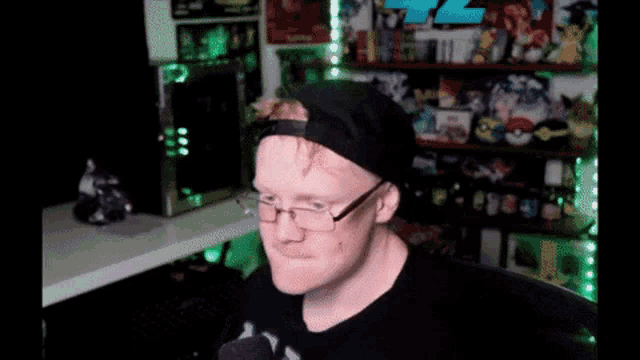 a man wearing glasses and a hat is sitting in front of a computer monitor
