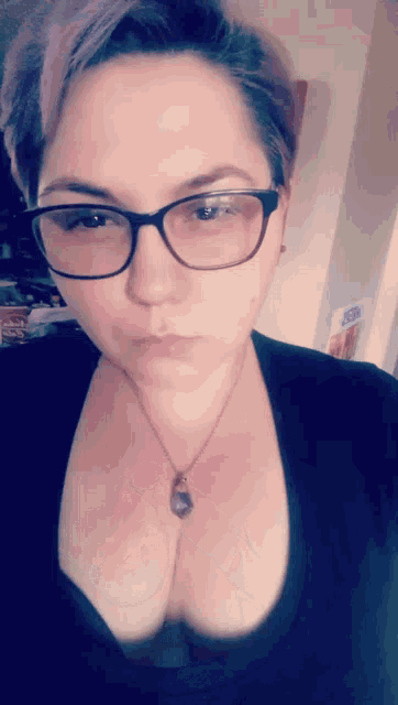 a woman wearing glasses and a necklace with a purple stone pendant