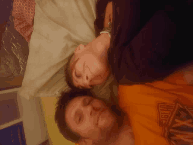 a man wearing an orange shirt that says eagle on it is laying next to a woman