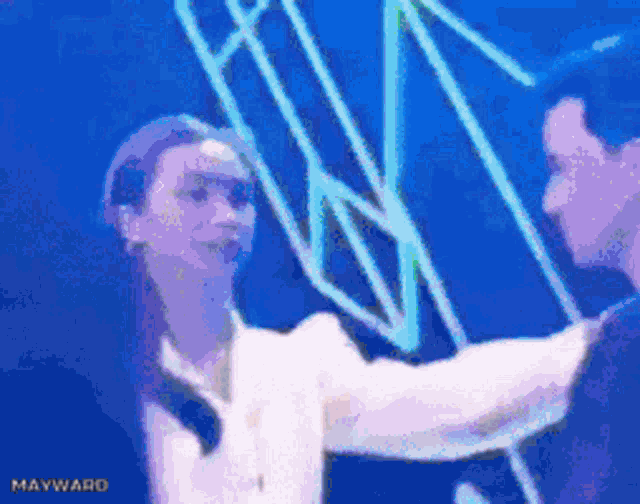 a man and a woman are hugging in front of a blue background with mayward written on it