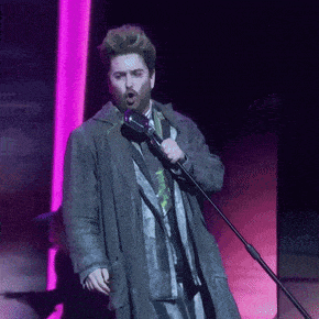 a man is singing into a microphone on a stage