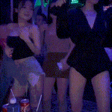 a group of women are dancing in a dark room while drinking coke .