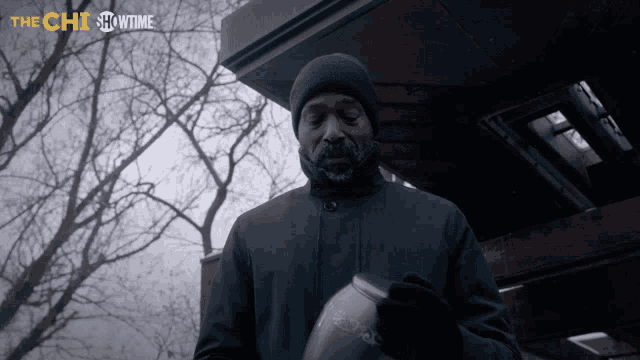a man holding a urn in front of a building that says showtime on it