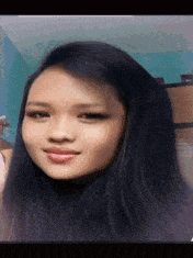a woman with long black hair is smiling and looking at the camera .