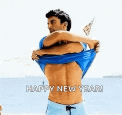 a shirtless man is taking off his shirt on the beach and says happy new year .