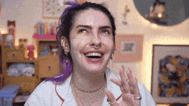 a woman with purple hair and a nose ring is smiling with her mouth open